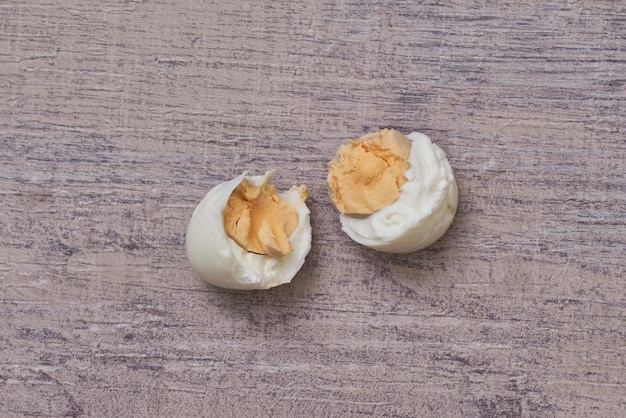 Top view of the boiled eggs cut in pieces on a wooden surface