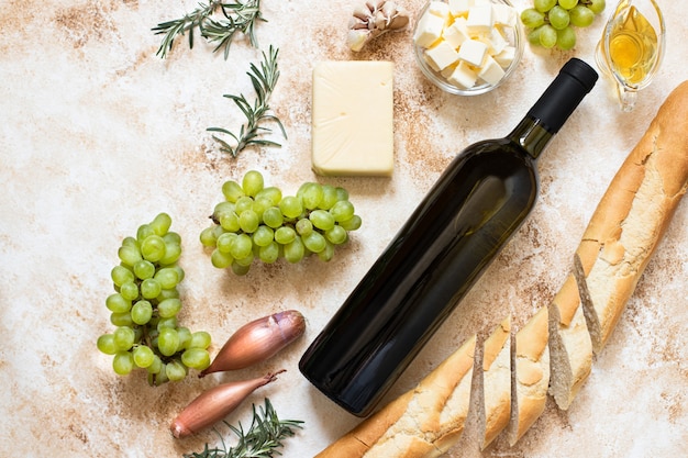 top view bottle of white wine, grapes, cheese, butter, and baguette