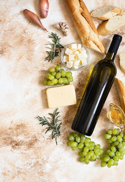 top view bottle of white wine, grapes, cheese, butter, and baguette