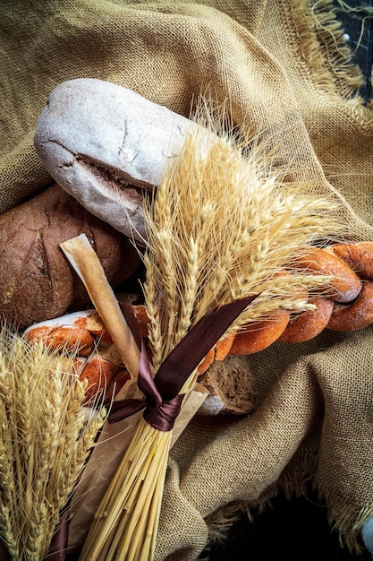 Top view of a bouquet of wheat lying on fresh bread and other bakery products as a symbol of food and agrarian wellbeing of the country