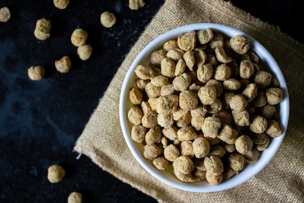 Top view of a bowl full of soya bean chunks on black background