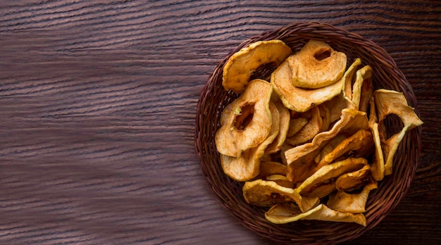 Top view of bowl with dried apple chips on wooden table