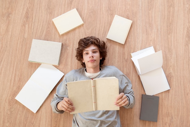 A top view of a boy teenager laying on the floor and reading books, learn and study