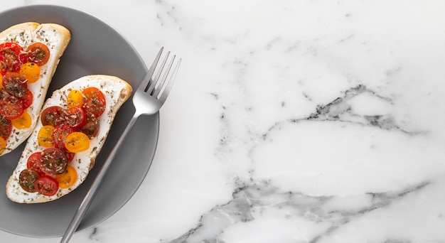 Top view bread with cream cheese and cherry tomatoes on plate with fork and copy-space