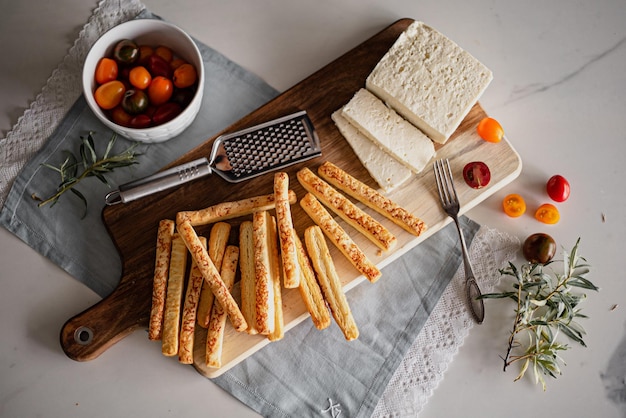 Top view of breadsticks with cheese and tomatoes on a wooden board