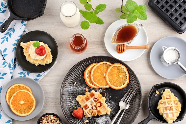 Top View Breakfast Setting Table with Croissant Waffle or Croffle, Strawberry, Sliced Orange, Honey, and Maple Syrup