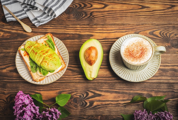 Top view of breakfast with sandwich avocado and a cup of cappuccino