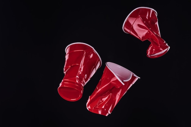 Top view of bright and colorful red plastic cups isolated on black with copy space