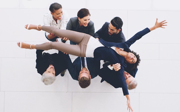 Top view business group and carrying woman with joy for successful deal and celebration in the office Celebrate success and businesspeople lifting a female staff member for cheering