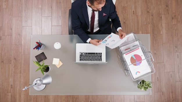 Top view of businessman analyzing company statistics documents working at financial strategy