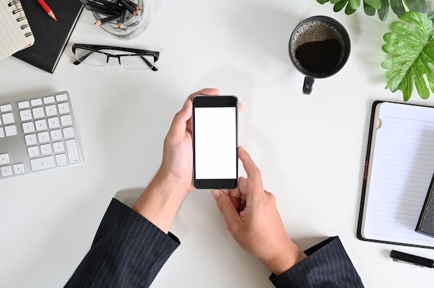 Top view businessman hands using mockup smart phone on office desk.