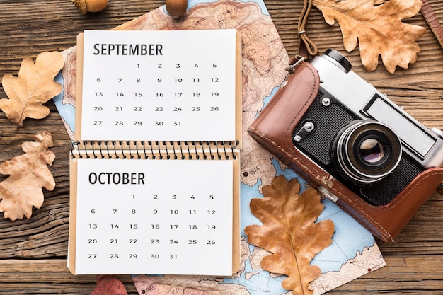 Top view of calendar with camera and autumn leaves