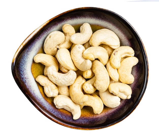 Top view of cashew seeds in ceramic bowl isolated