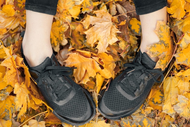 Top view of casual woman black sneakers in the autumn leaves