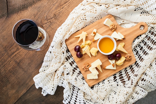 Top view of a cheese mix of Parmesan, Mozzarella, Camembert on a wooden Board and a glass of red wine