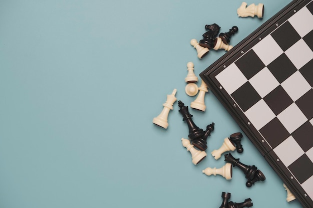 Top view of chess pieces with chess board on blue background for leisure and business strategy concept.