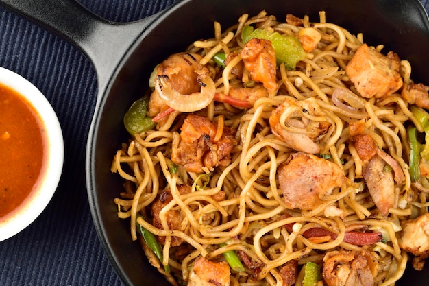 Top view of chicken noodles in plate with sauce