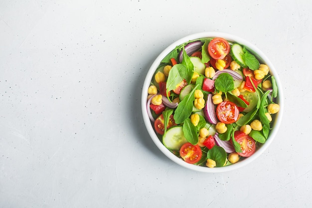 Top view of chickpea salad prepared with tomatoes, cucumber, red onion, cress salad and arugula. Chickpeas are rich in protein and fiber. Copy space