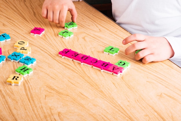 Top view of Child arm learning alphabet with puzzlein the table Copy space Learning in the form of a game concept