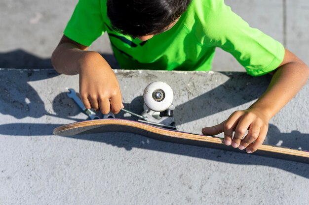 Top view of a child repairing the wheels of his scooter with a wrench.