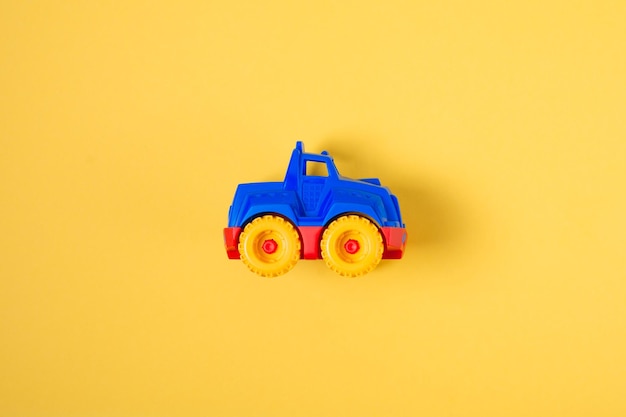 Top view children's toy car on a yellow background with copy space