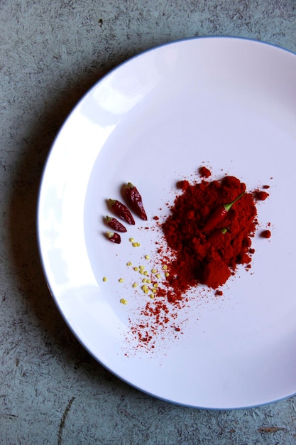 Top view of chili pepper and paprika in white plate with gray background