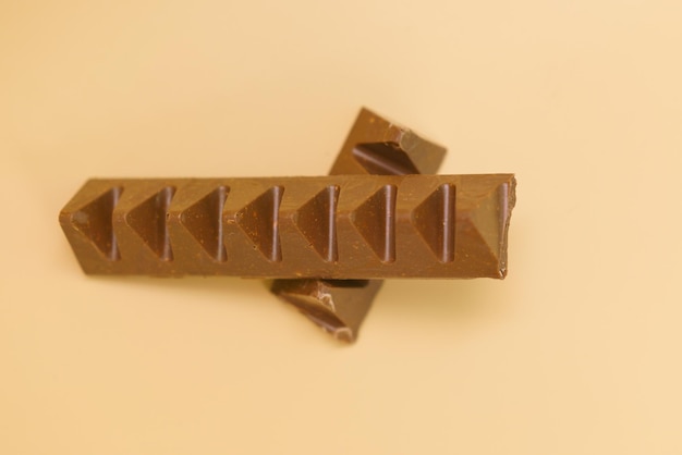 Top view of chocolate bar in a pyramid shape on a yellow background Relax Reward Mini Simple Decorate Milk One Shape Decorative Caffeine Choc Tasty Nuts