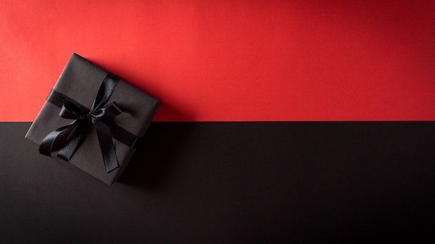 Top view of Christmas boxes with black ribbon on black and red wall with copy space for text. Black Friday composition.