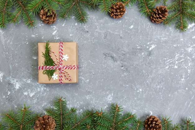 Top view of Christmas decoration with fir tree and gift box on gray cement table