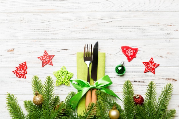 Top view of christmas decorations on wooden , Fork and knife on napkin tied up with ribbon and empty space