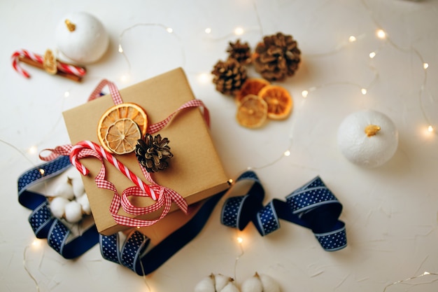 Top view of christmas gift box and decorations on white textured table candy cane colorful ribbons g...