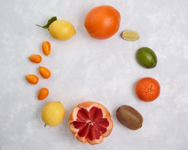 Top view of citrus fruits as orange lime kumquat lemon kiwi grapefruit on white background