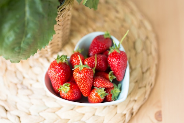 Top view close up of heart shaped Bowl of fresh strawberry on the table. Free space. Copy space. Summer concept.