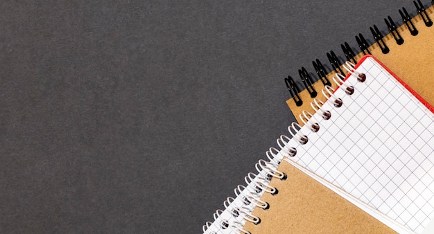 Top view of closed black cover notebook with pencil on white desk background