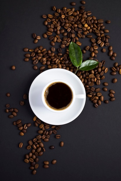 Top view of coffee cup and coffee beans on the black background.  Close-up. Location vertical.