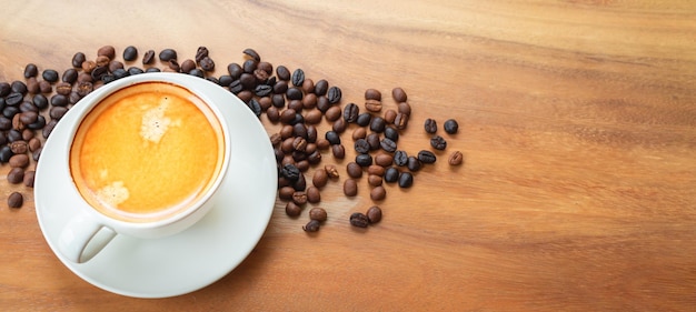 Top view of coffee cup has golden foam and mixed or blend coffee beans on wooden backgrou