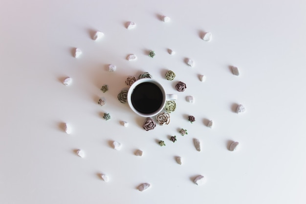 Top view of coffee on white background with flower and stones in circle