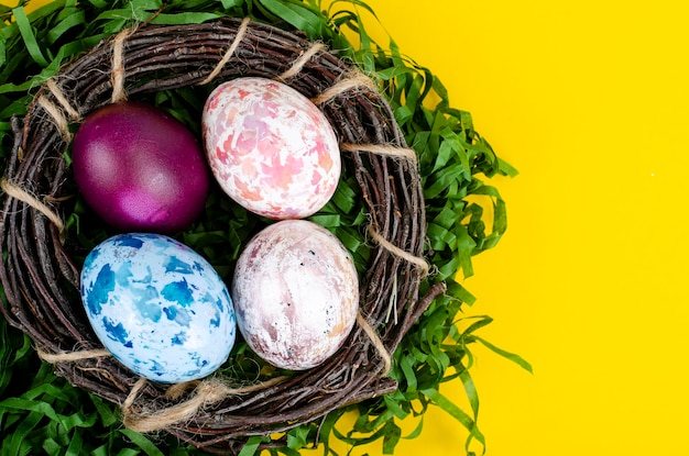 Top view of color easter haqndmade eggs and nest flatlay. Trendy minimal design spring  background. Space for text. Stuio Photo