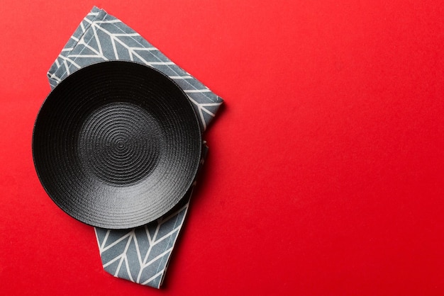 Top view on colored background empty round black plate on tablecloth for food Empty dish on napkin with space for your design