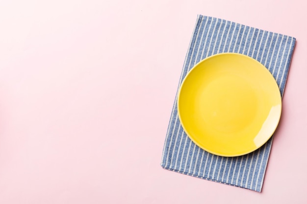 Top view on colored background empty round yellow plate on tablecloth for food Empty dish on napkin with space for your design