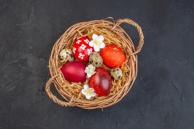 top view colored easter eggs inside basket on dark surface