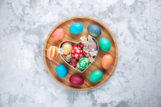 top view colored easter eggs inside heart shaped box and on cutting board white surface holiday concept easter ornate colourful