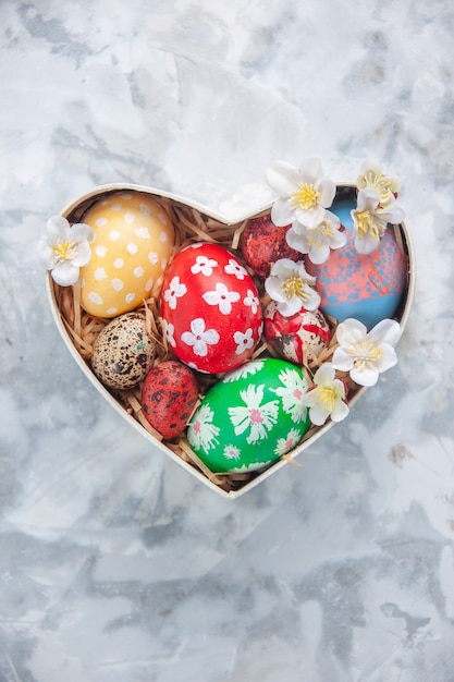 top view colored easter eggs inside heart shaped box on white surface concept ornate colourful spring holiday paint