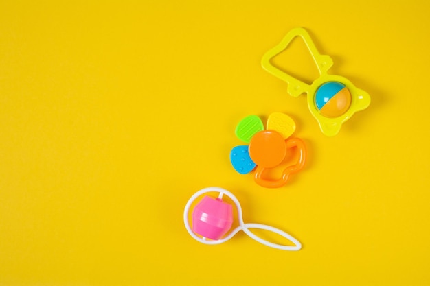 Top view a colorful baby rattle on yellow background Newborn rattle toy on colored background