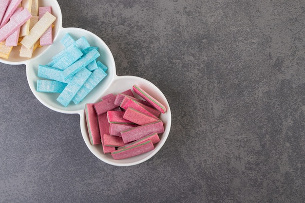 Top view of colorful gums on white plate over grey background. 