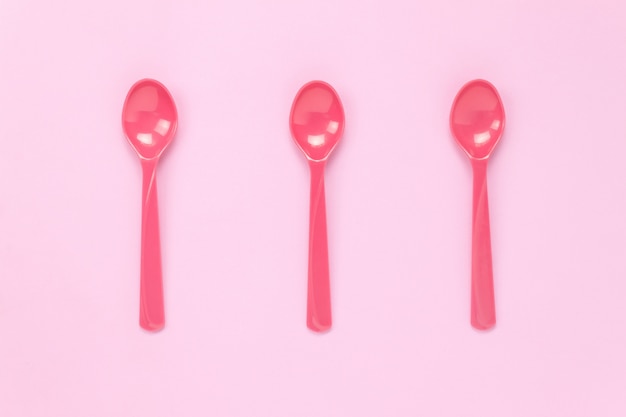 Top view colorful plastic spoon on pink table background with copy space.