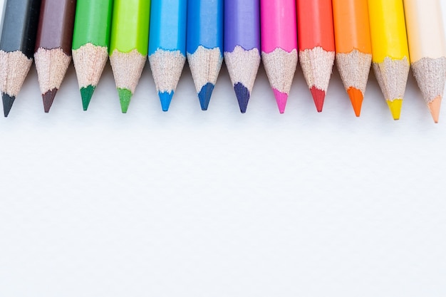 Top view of colourful crayons or colour pencil set in range on white paper