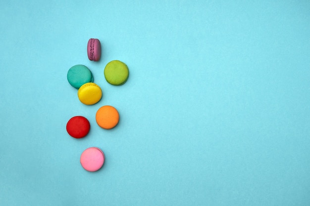 top view composition colored sweet French cakes macaroni cookies lie on an isolated blue background