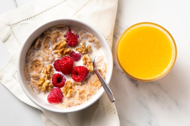 Top view composition of healthy bowl cereals with orange juice