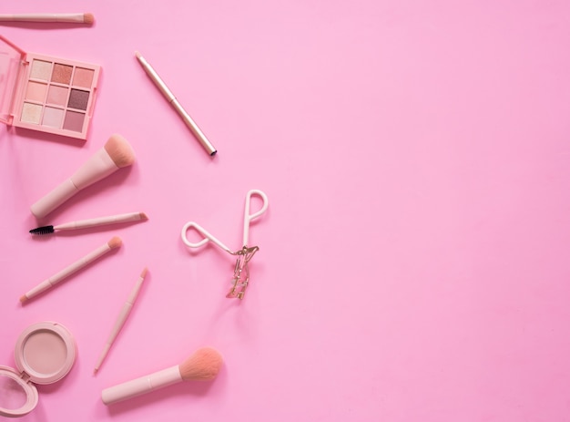 Top view composition set for professional makeup on pink background.